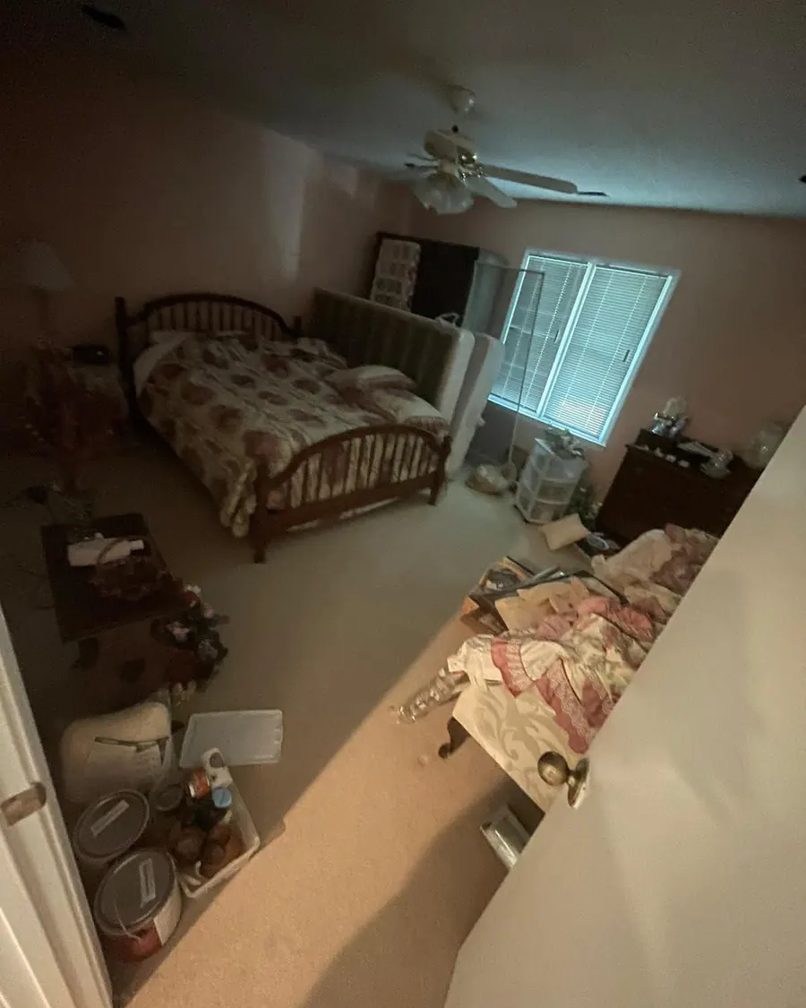 Bedroom with worn carpet and furniture pushed aside before the floor was replaced