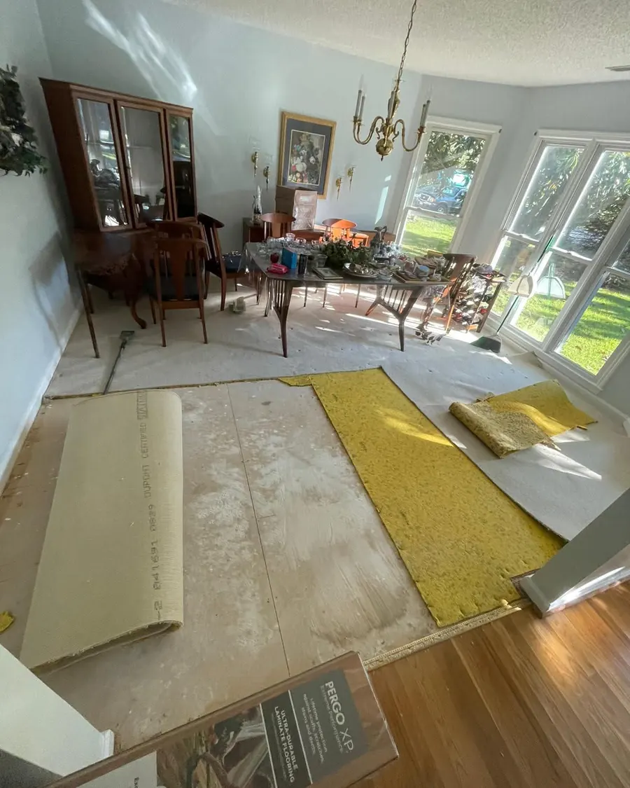 Dining room stripped back with underlayment down and planks staged, mid-install