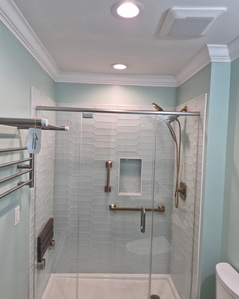 Finished tiled shower with a glass door and brass fixtures