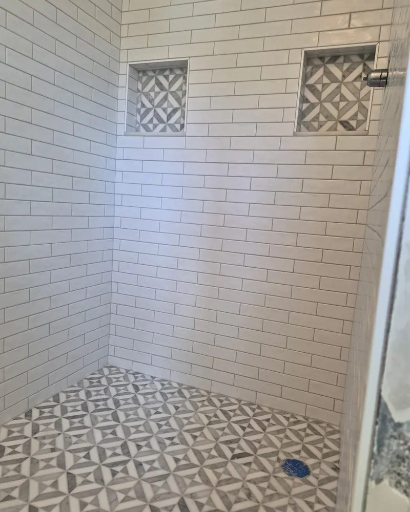 White subway tile shower with a patterned mosaic floor