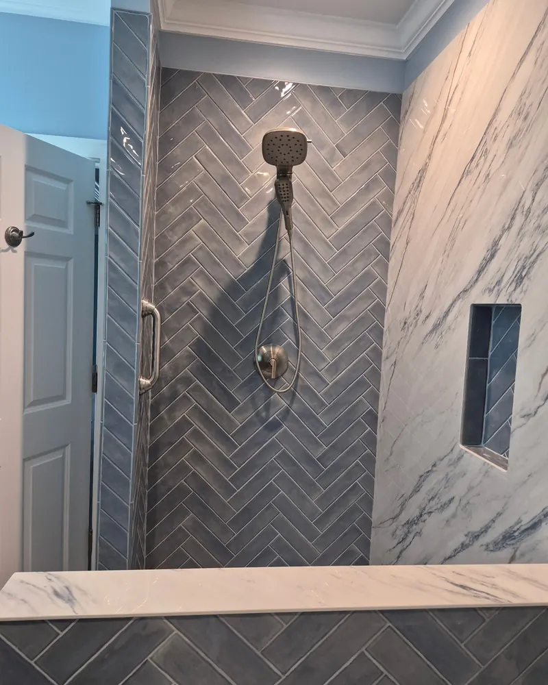 Herringbone shower wall with a marble bench and shelf