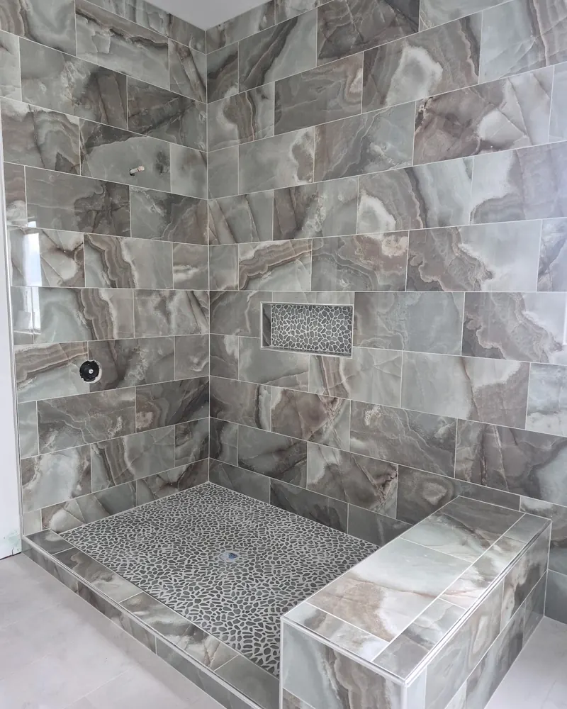 Marble-look shower with a mosaic niche and pebble floor
