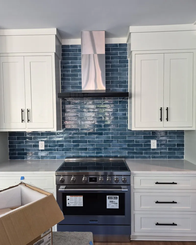 Blue glass subway backsplash running full height behind a range