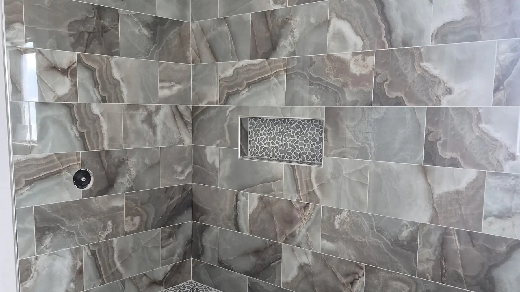 Marble-look porcelain shower walls with a mosaic niche