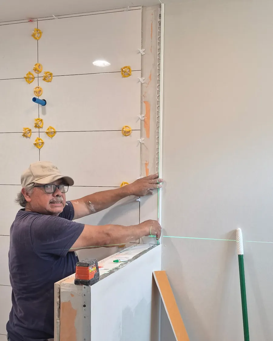 Olguin setting wall tile to a laser line, levelling clips fitted