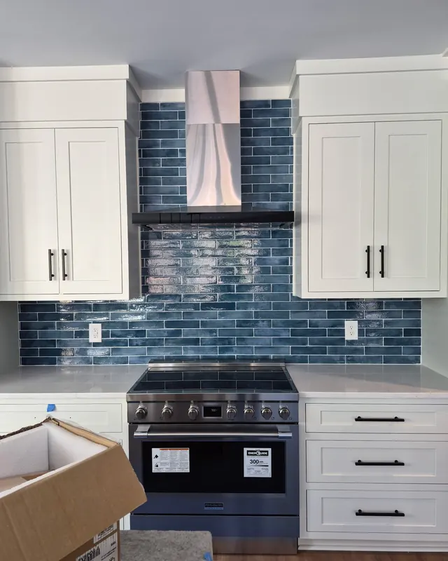 Blue glass subway backsplash behind a range